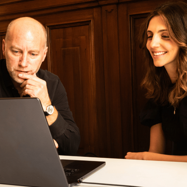 Two Clear Europe team members reviewing content together on a laptop in a wood-panelled office.